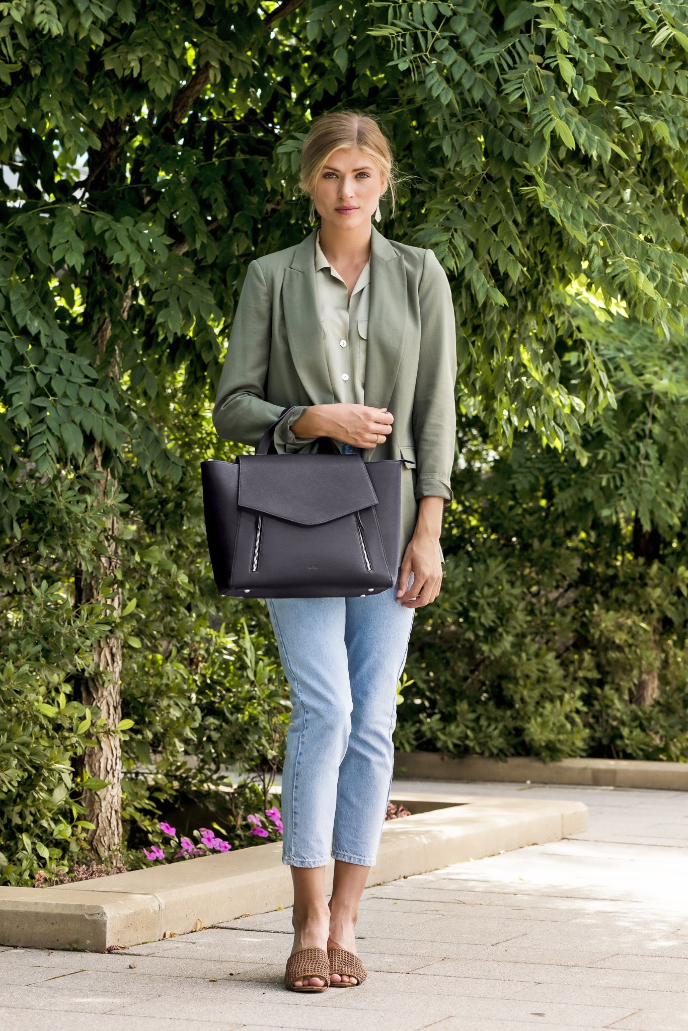 Woman carrying AGIKI Classic Black convertible leather laptop work bag for women while standing outdoors